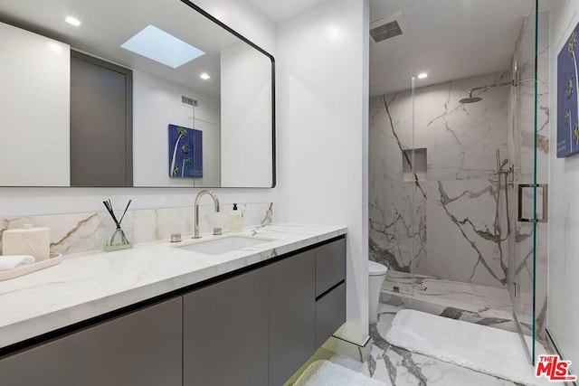 bathroom with vanity, toilet, a shower with door, and a skylight