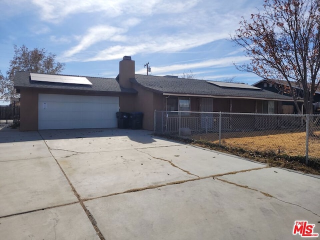 ranch-style house with a garage and solar panels