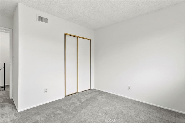 unfurnished bedroom with a textured ceiling, light colored carpet, and a closet