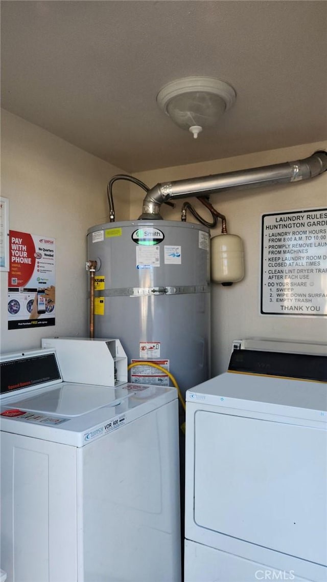 washroom with strapped water heater and washing machine and clothes dryer