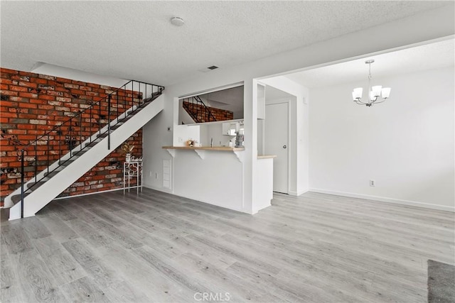 unfurnished living room with hardwood / wood-style floors, a chandelier, and a textured ceiling