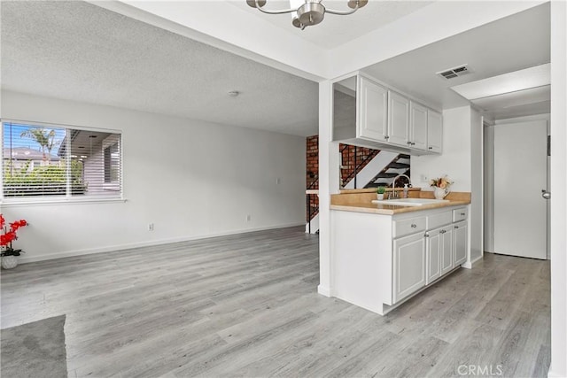 kitchen featuring light wood-type flooring, white cabinetry, and sink