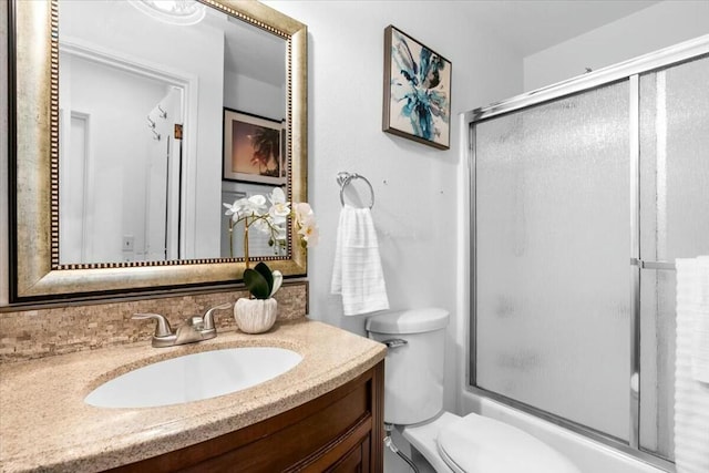 full bathroom featuring vanity, toilet, and shower / bath combination with glass door