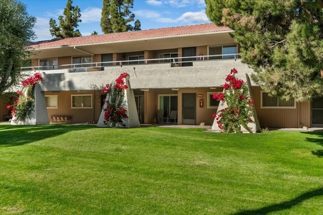 back of house with a yard and a balcony