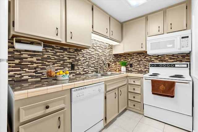 kitchen featuring tile countertops, cream cabinets, light tile patterned floors, and white appliances