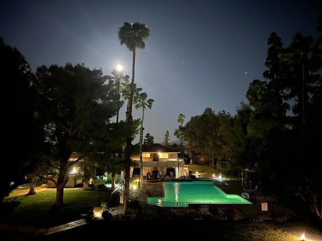 pool at night featuring a patio