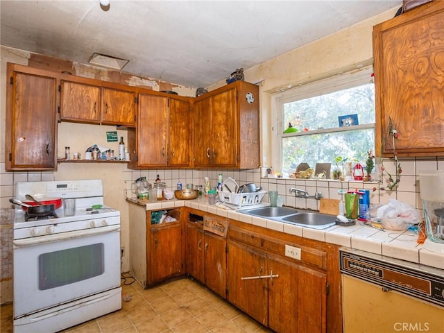 kitchen with white gas range oven, tasteful backsplash, tile counters, and sink