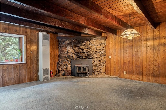 unfurnished living room with a wood stove, beamed ceiling, carpet floors, and wooden ceiling