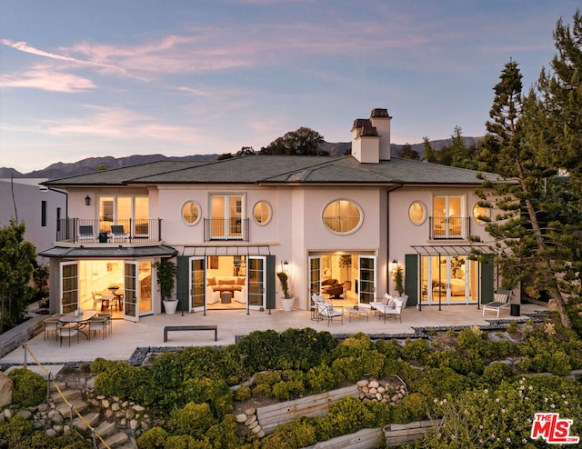 back house at dusk with a balcony