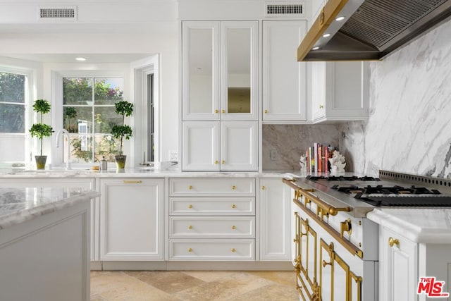 kitchen featuring white cabinets, stainless steel gas stovetop, custom range hood, and sink