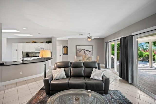 living room with light tile patterned floors, a skylight, ceiling fan, and sink