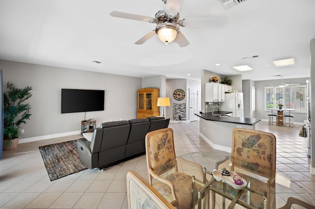 tiled living room featuring ceiling fan and sink