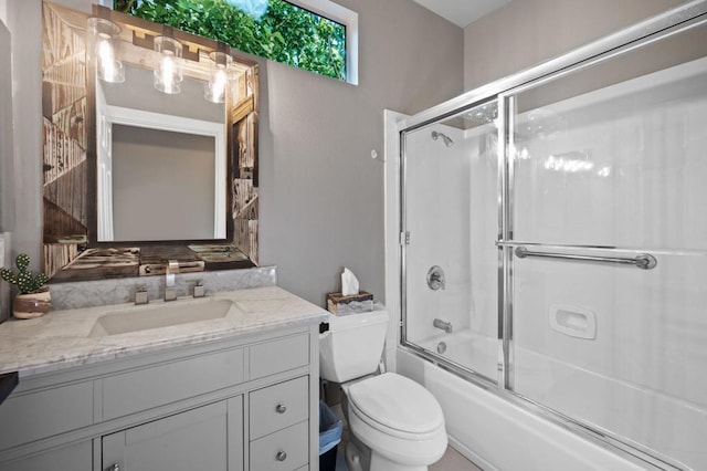 full bathroom featuring combined bath / shower with glass door, vanity, and toilet