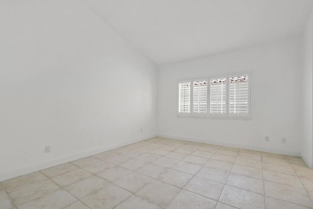 spare room featuring vaulted ceiling and light tile patterned flooring