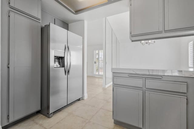 kitchen featuring light tile patterned flooring, gray cabinetry, and stainless steel fridge