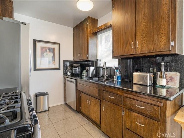 kitchen with decorative backsplash, sink, light tile patterned floors, and stainless steel appliances