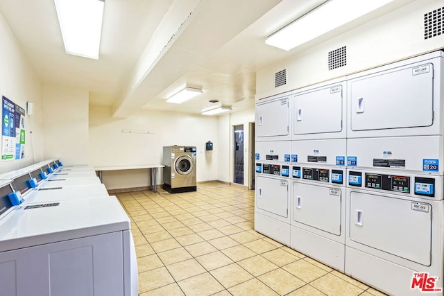 laundry area with light tile patterned floors, stacked washer / drying machine, and washing machine and clothes dryer