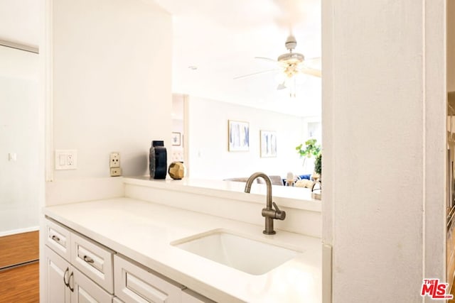 kitchen with ceiling fan, white cabinets, hardwood / wood-style flooring, and sink