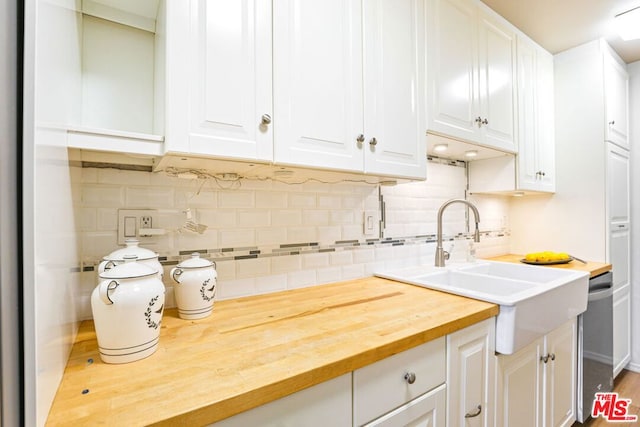 kitchen with butcher block counters, white cabinets, tasteful backsplash, and sink