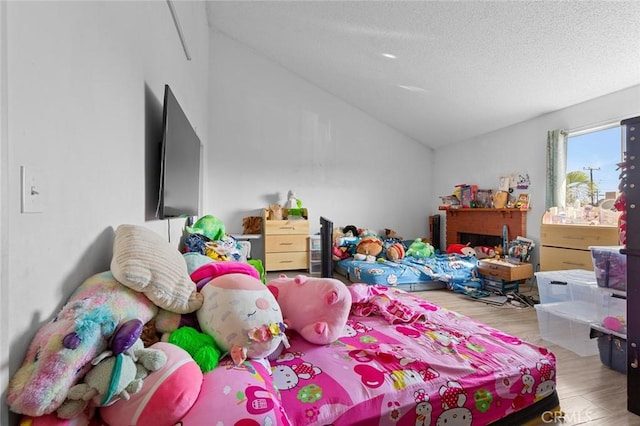 bedroom featuring vaulted ceiling, hardwood / wood-style floors, and a textured ceiling