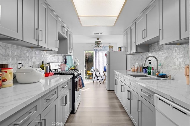 kitchen featuring gray cabinetry, ceiling fan, white appliances, and sink