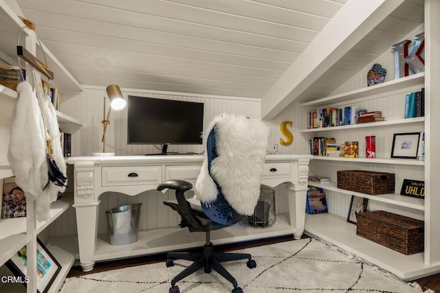 office featuring wood walls, lofted ceiling with beams, and hardwood / wood-style flooring