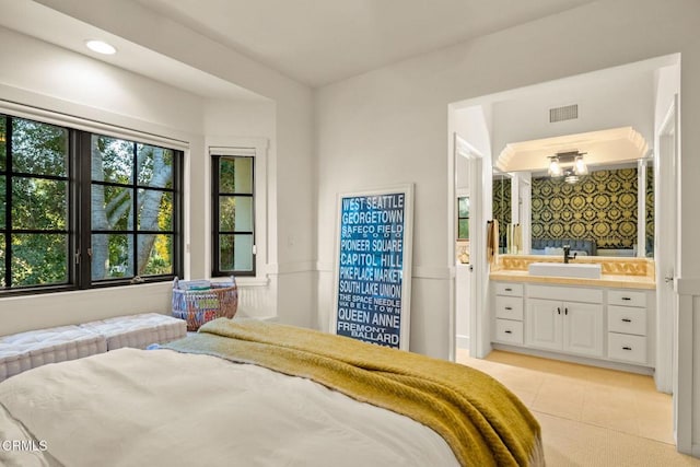 bedroom featuring light tile patterned flooring, ensuite bathroom, and sink