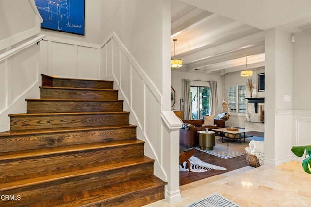 staircase featuring hardwood / wood-style flooring, ornamental molding, and beamed ceiling