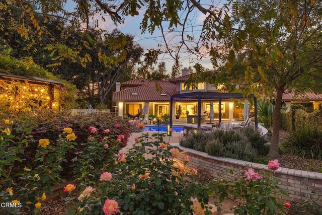 back house at dusk featuring a patio area