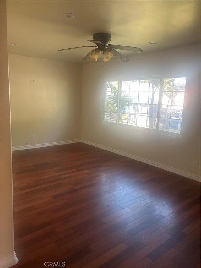 spare room featuring a wealth of natural light, ceiling fan, and dark hardwood / wood-style floors