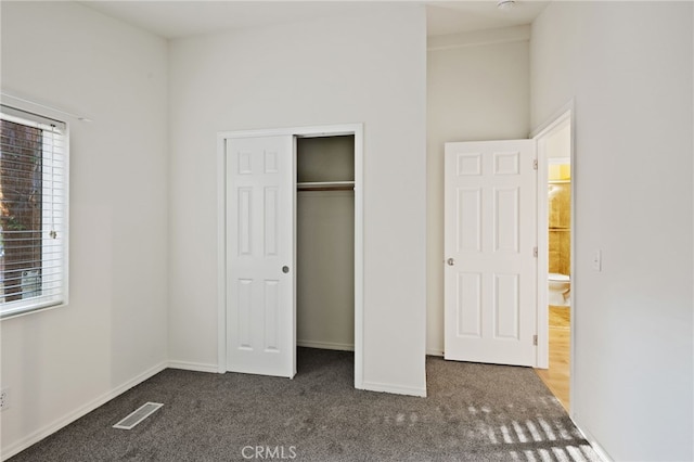 unfurnished bedroom featuring a closet and dark carpet