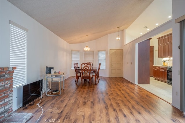 dining room with wood-type flooring, a textured ceiling, an inviting chandelier, and plenty of natural light