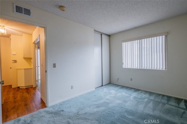 carpeted empty room with a textured ceiling