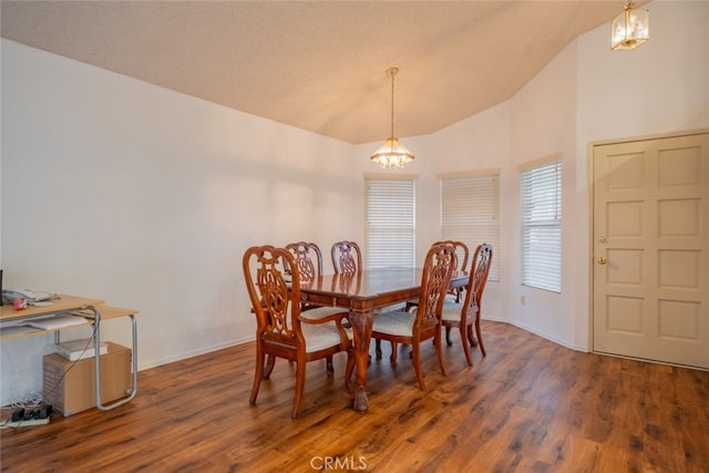 dining area with high vaulted ceiling, dark wood-type flooring, and a notable chandelier