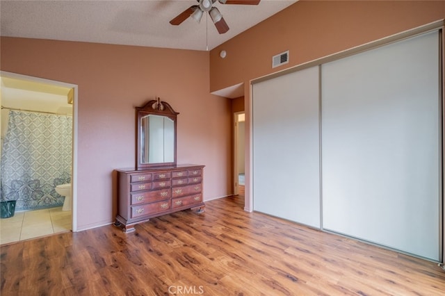 bedroom featuring ensuite bathroom, light hardwood / wood-style flooring, ceiling fan, a textured ceiling, and a closet