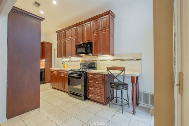 kitchen with tasteful backsplash, a breakfast bar, light tile patterned flooring, and black appliances