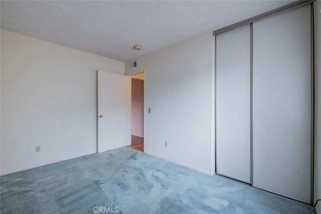 unfurnished bedroom with carpet flooring, a textured ceiling, and a closet