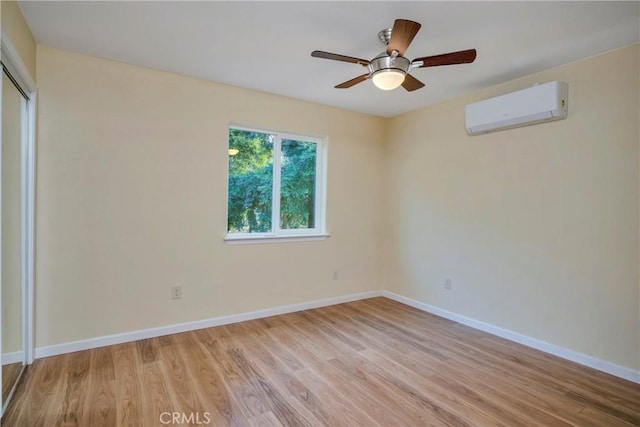 empty room with light hardwood / wood-style floors, ceiling fan, and a wall mounted air conditioner