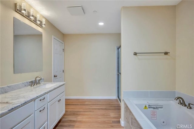 bathroom with hardwood / wood-style floors, tiled tub, and vanity