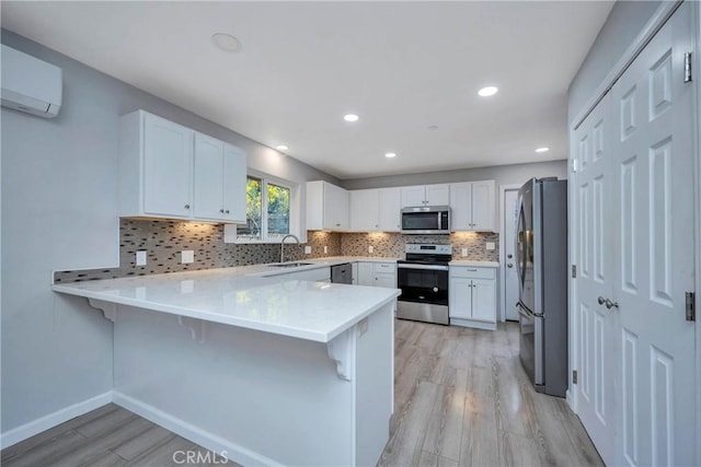 kitchen with stainless steel appliances, white cabinets, kitchen peninsula, and a breakfast bar