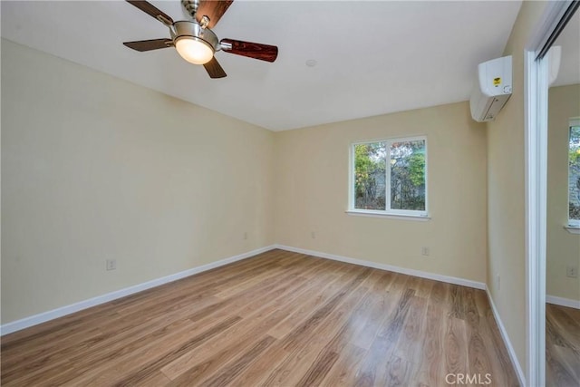 spare room with a wall unit AC, ceiling fan, and light hardwood / wood-style flooring