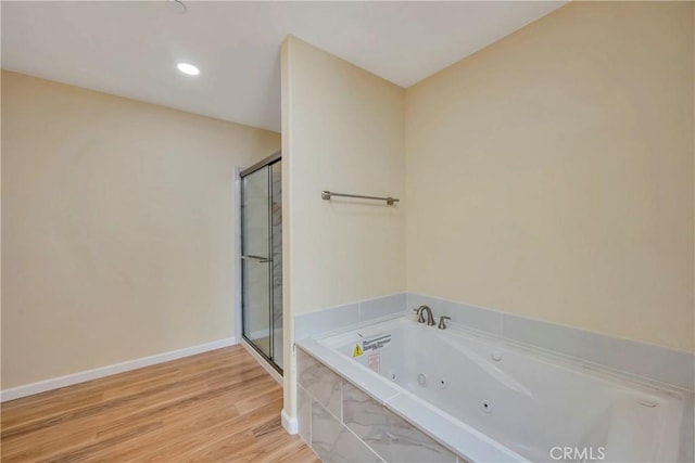 bathroom with a tub to relax in and hardwood / wood-style flooring