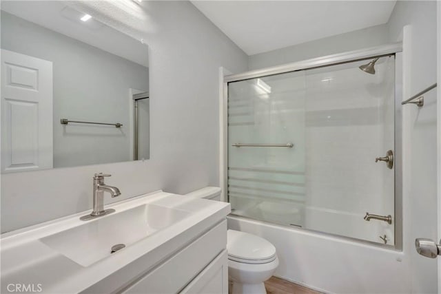 full bathroom featuring hardwood / wood-style floors, enclosed tub / shower combo, vanity, and toilet