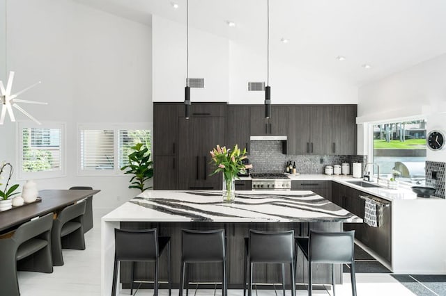 kitchen featuring backsplash, sink, high vaulted ceiling, a center island, and hanging light fixtures