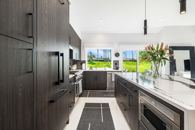 kitchen with appliances with stainless steel finishes, tasteful backsplash, sink, pendant lighting, and light tile patterned flooring