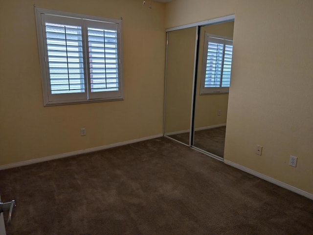 unfurnished bedroom featuring a closet and dark carpet