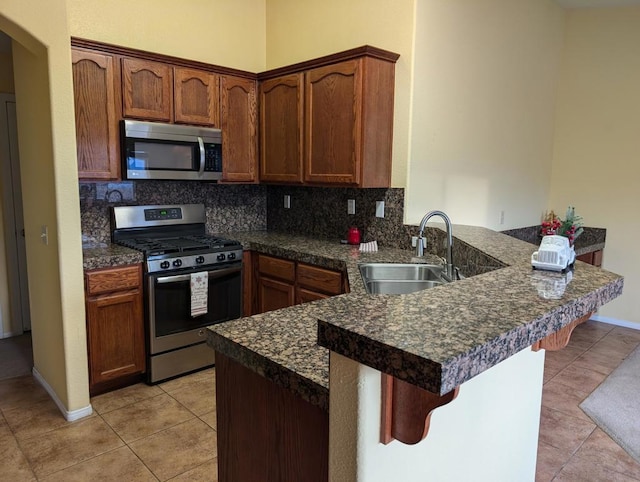 kitchen featuring kitchen peninsula, appliances with stainless steel finishes, backsplash, and sink