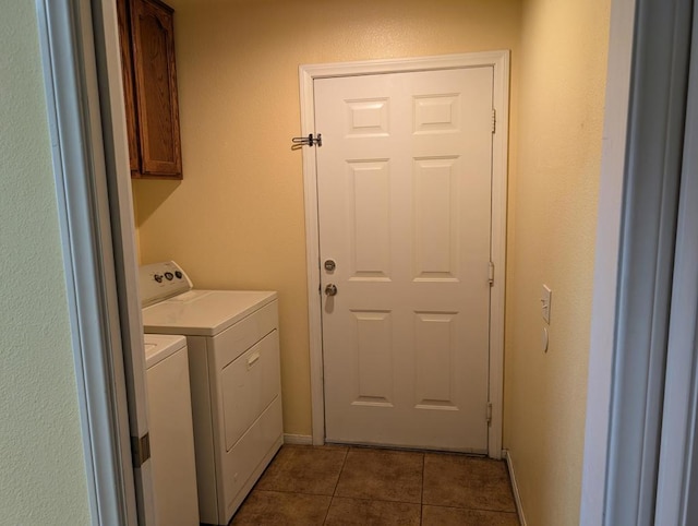 clothes washing area with cabinets, dark tile patterned floors, and washer and clothes dryer