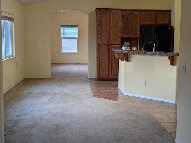 kitchen featuring black fridge, a breakfast bar, and light tile patterned floors