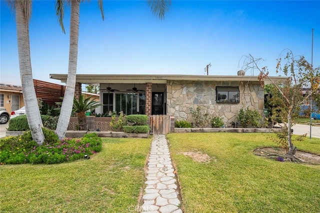 view of front facade with ceiling fan and a front yard